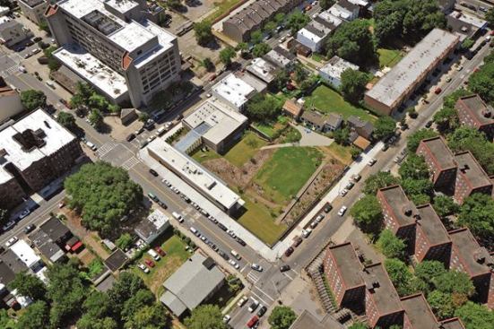 An+aerial+view+shows+how+the+new+center+frames+the+four+historic+houses+(at+upper+right)+on+the+1.5-acre+site.+Where+not+bounded+by+buildings%2c+the+perimeter+is+enclosed+by+a+cast-iron+fence+from+Allen+Architectural+Metals.+