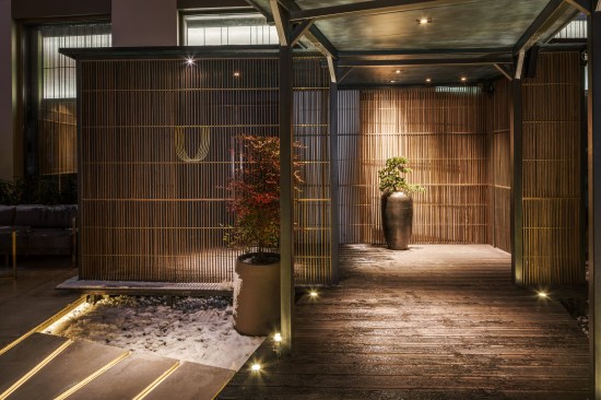 The entrance screen is teak fixed by brass rods, with a logo made of laser-cut brass on the right.