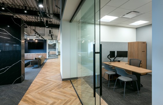 Glass-fronted private offices with soft-close doors around the perimeter surround a generously proportioned open office.