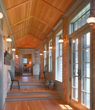 Mountaintop House Cloister-Mt. Desert Island, ME The linear "cloister" shown here links the main rooms of the first floor of a mountain camp overlooking a harbor in Maine. The cloister is a one-story shed along the south flank of this two-story house, which lowers the scale on the side facing the main outdoor living space. Cedar shingles clad the interior of this passageway, giving it a rustic, outdoor character and differentiating it from the living spaces, which are finished with horizontal fir boards. The cloister also defines the principal axis of the house, which is perpendicular to the slope of the site. With this orientation, the first floor steps downward, while the second floor remains constant. The main living spaces, which open off the cloister, progress with increasingly high ceilings from cozy at the entry level to grand facing the view. 
Architect: Albert, Righter&nbsp;& Tittmann Architects