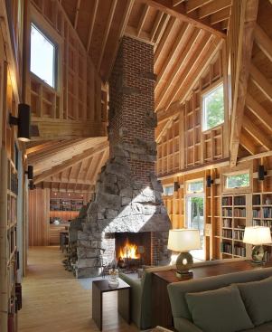Lake Island Camp-Central New Hampshire This lake camp was designed for clients in 1969, and 40 years later they returned to design another camp on an adjacent part of the same land. The prismatic roof of the new Lake Island Camp is perhaps its most striking feature, recalling the angular roof of its predecessor. The exposed framing shown here in the living room emphasizes the Origami-like roof folds. The complex roof lends spatial excitement to a simple, rectangular plan. The double-sided fireplace is the focal point in the otherwise open living, dining, and kitchen area. Local granite on the chimney transitions into brick as it passes through the roof. Cavities in the open stud spaces provide ready-made places for bookshelves. 
Architect: Albert, Righter&nbsp;& Tittmann Architects
