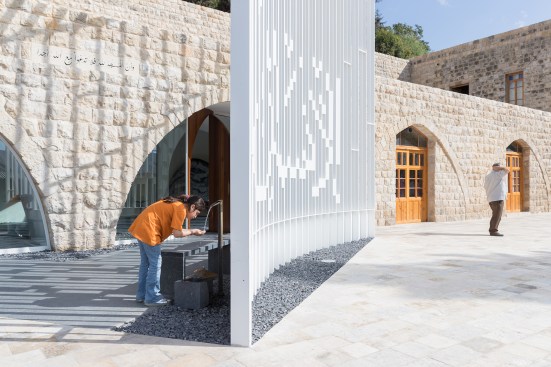 View of entry, showing wall of steel slats inscribed with “Insan”