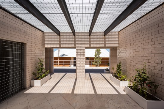 View from a courtyard in the MOS-designed welcome and education center at the Apan Housing Laboratory in Apan, Mexico, out to the affordable house prototypes.