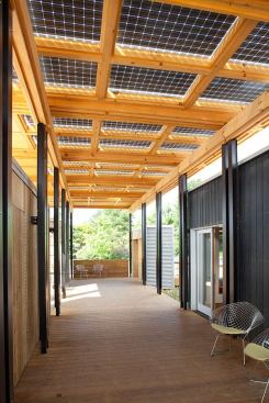 Shaded by bifacial solar panels that collect reflective light from underneath as well as direct sunlight that shines above, the OMs can be configured in various ways to provide protection from harsh mountain weather while still allowing cool breezes or warming winter sun to maintain pleasant conditions on the porch as well as inside the main house.