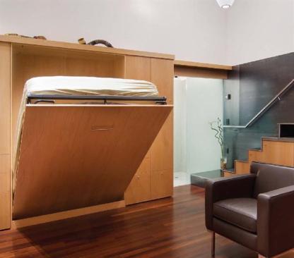 Beyond the sleek Murphy bed  etched glass pocket doors screen the combination bath laundry closet in this hardworking space.