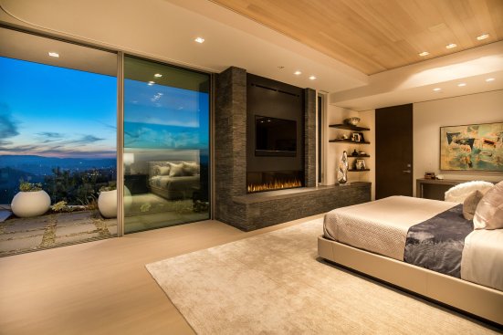 Warm modern bedroom design with fireplace and terrace access.