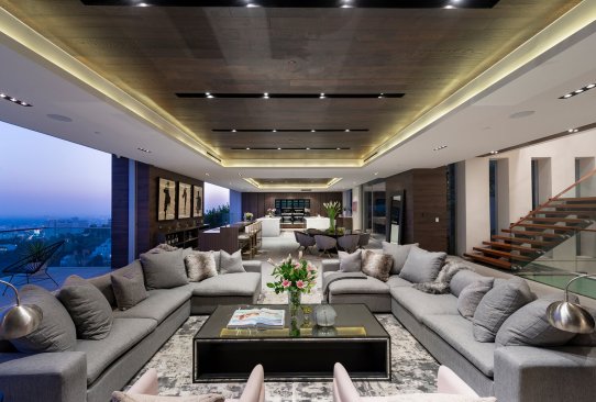A modern kitchen opens up to an outdoor dining patio through sliding glass walls.