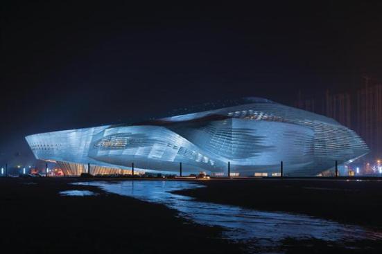 At+night%2c+dramatic+lighting+plays+off+of+the+parametrically+designed+aluminum+skin+of+the+Dalian+International+Conference+Center.