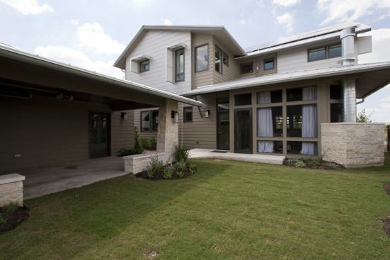 The carport helps extend the backyard for entertaining or play. The second-story windows sport cloth awnings to reduce solar heat gain.