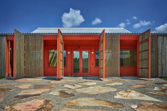 In the headquarters building, slatted wood doors on steel frames open the reception area to the plaza