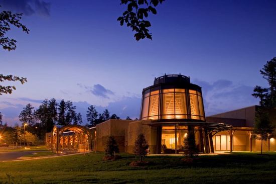At the corner of the building is the circular library/sitting room illuminated with the same indirect lighting of the warm natural materials that are used throughout the Center.