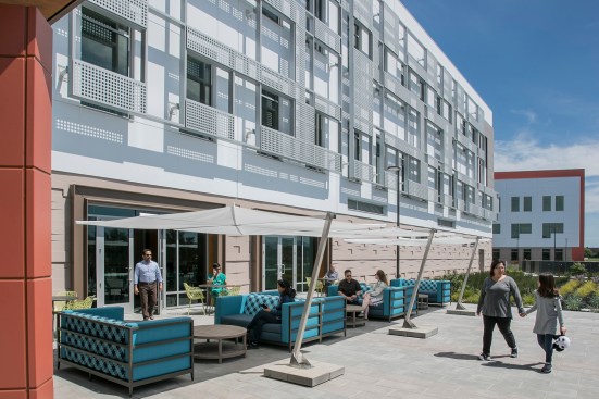 The custom-designed solar sunshade one the south façade creates varying shadows on the wall above an outside seating area for the café.