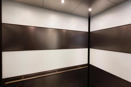 LEVELe-104 Elevator Interior with main panels in ViviChrome Chromis glass, White interlayer, Opalex finish; upper accent and handrail panels in Fused Nickel Silver, Sandstone finish; lower accent panels in Fused Nickel Silver, Sandstone finish, Dallas Impression pattern at 1000 Broadway, Portland, Oregon