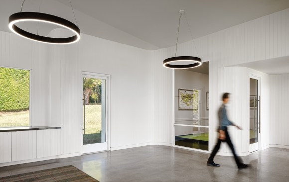 Multipurpose exercise area with curved walls of vertical wood planks; the window views into the practice putting studio with the undulating moving floor