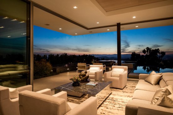 Modern design living room with open sliding glass walls that let in the sunset view.