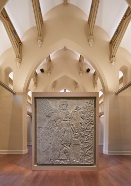 Surface-mounted, adjustable accent luminaires with narrow optics graze the replica panel from a high point above the arch wall.