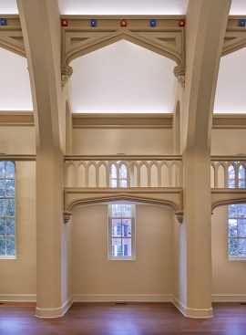 The bearing walls are washed with concealed linear wall-wash luminaires mounted behind purlin arches. Tape light integrated below the balconies washes the lower walls.