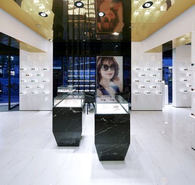 A general view of the store interior. 4000K adjustable LED downlights aim down to the floor, creating an evenly distributed glow on the white marble floors, which is then reflected on the gold ceiling.