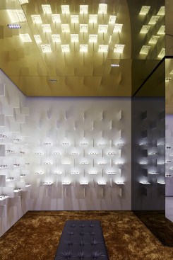 The gold-toned ceiling and the  gold-hued carpet provide a contrast to the white backdrop of the main eyewear displays.