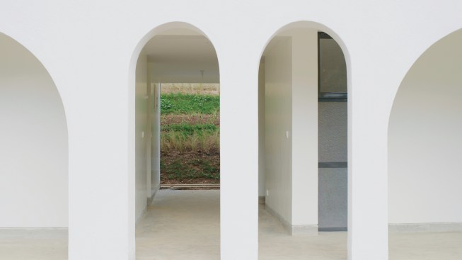 The arches were built out of locally fired brick supported on piers of concrete masonry units. The surfaces are covered in white plaster to create an even surface and bounce light into the building. 