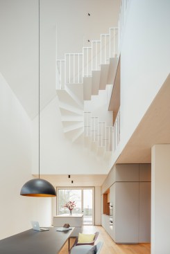 Above the dining area, an air space extends to below the pitched roof and forms a vertical "L" with the open kitchen or living space.