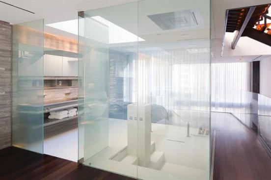 The bath separates the master bedroom from a private study, but its transparency creates the sense of a single continuous space.