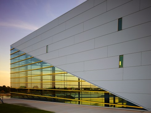The sculptural building prow incorporates symbolic lines as if ripples in the water.  A surprising overlap of two gold window “notes” make the interior volume known.