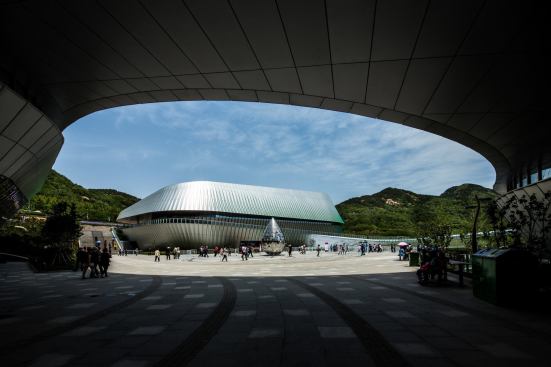 View from underneath one structure to another pavilion across a landscaped plaza.