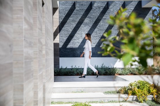 Modern Beverly Hills home front entrance with stacked stone walls and outdoor covered walkway.