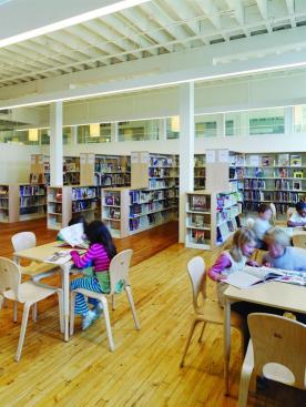The second-floor library is a good example of the school?s overall materials palette. Walls are painted in Chantilly Lace, an off-white low-VOC paint from Benjamin Moore. Light wood furniture from Community Playthings and maple shelving (a collaboration with Ross McDonald & Co.) allow for a neutral and focused study environment, and direct/indirect P-60 linear light fixtures from Prudential Ltg. supplement natural daylight.