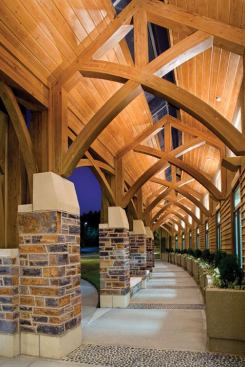 Behind the domed entryway, the wooden ceilings of the connecting exterior corridors are indirectly lit from the 3000K metal halide sconces mounted on the building sidewall.