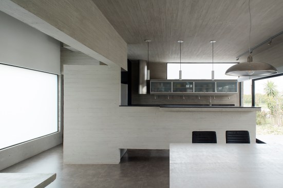 The house’s muted color and material palettes prevail throughout the interior, as seen here in the first-floor kitchen and dining areas.