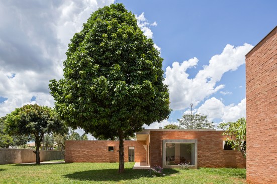 The bedrooms and other private spaces are located at the rear of the house. The architect sited the building to preserve the existing trees, which are protected in BrasÍlia. A small brick outbuilding (at right) serves double duty as a dog house and a water cistern.