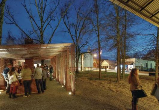 The+new+town+square+has+become+a+gathering+place+for+the+residents+of+Newbern.+Seen+here+from+under+the+overhang+of+the+town+hall+roof%2c+residents+gather+in+the+barbecue+pit+that+bridges+the+plaza+between+the+town+hall+and+the+fire+house.+Across+the+street%2c+the+next+Rural+Studio+project+in+Newbern+is+under+way%3a+a+new+library.