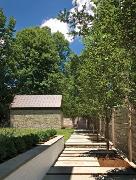 The building opens up—both stylistically and literally—to a neatly tailored backyard with an elegant storage shed.