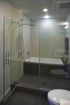 To make better use of space, the bathtub in this unit is located within the shower enclosure. The light gray tile surround was made with Walker Zanger Eco Tile.