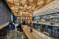 Glowing plywood ceiling illuminated by Type A–lamp pendants above dining area
