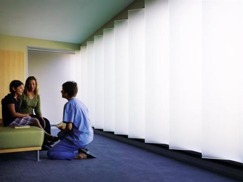 A translucent louvered wall in the general surgery waiting room allows both natural light and privacy for people waiting for procedures or families waiting for loved ones. Carpet: Monterey; Tribeca broadloom collection with Lifespan polyurethane backing in Staten Island; colorway tandus.com - Upholstery: Maharam; C220 upholstery fabric; maharam.com