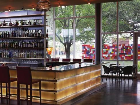 The bar at The Grove is clad in glowing panels that mimic a rich material like alabaster. The effect is achieved by using 3form resin panels back-lit by fiber-optic strands that give the panels a gentle glow. Those perched on a bar stool enjoying one of the restaurant?s signature drinks also have a frontrow view of artist Margo Sawyer?s wall of color blocks, a feature that fits well with Discovery Green?s commitment to public art.