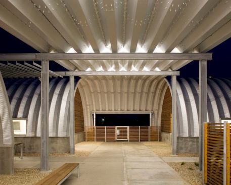 A covered exterior walkway connects the three huts. T5 striplights are positioned in custom break-metal shields to accentuate the canopy and provide diffuse illumination for the building entries, walkways and seating areas.