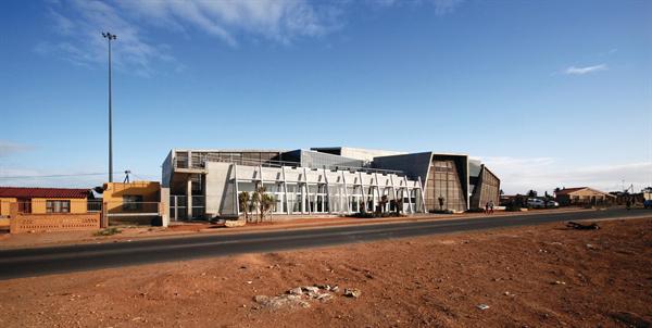 The north face runs along the township's main street; volumes hold flexible meeting spaces (with a vegetable garden on the roof) and a staff lounge.