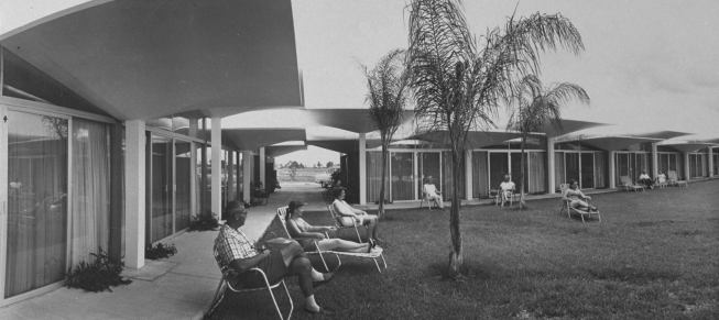 People+relaxing+in+lounge+chairs+in+courtyard+at+new+resort+motel+with+a+parasol+roof+made+of+75+concrete+umbrellas+joined+with+plastic.