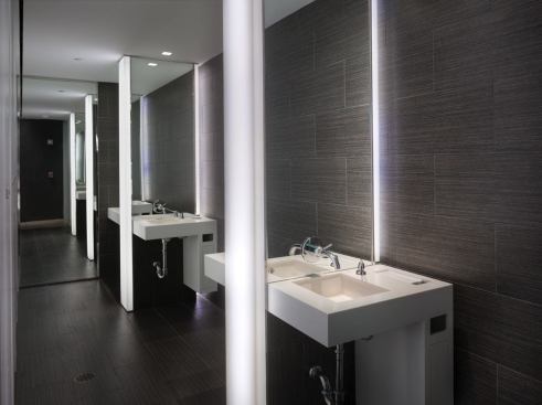 In the restroom, the sink appears to float off of the wall because of the LED fittings installed behind the resin lenses. The fixture also provides a warm glow on an occupant's face.