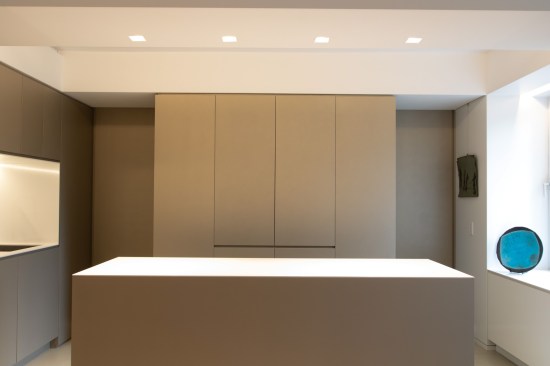 The appliance garage hides all the clutter for the minimalist owners. Two pocket doors in the volume can be closed for separation to the bedroom, or opened for the reading of one larger space. The appliance garage cabinet doors also can fully pocket into the cabinet for ease of use. Recessed finger pulls are used throughout the apartment for a super clean, minimal look without any hardware.