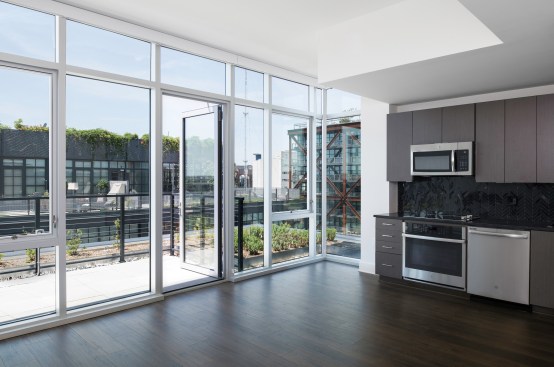 Floor-to-ceiling windows open onto a private terrace showcasing views of the neighborhood.
