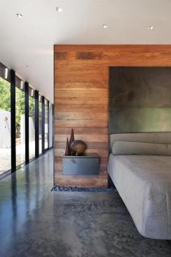 A band of rocks intersects the ground and wall plane in the master bedroom. Local walnut visually warms the concrete floors. 