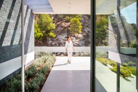 Pivot glass front door and covered walkway at entrance to Beverly Hills modern home.