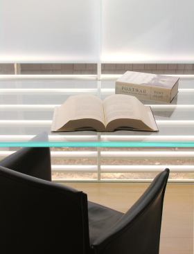 Detail of a small glass-enclosed office niche. The desk and drawers slide between steel supports.