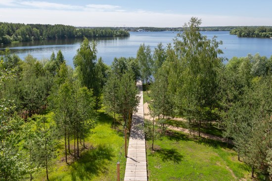 A lit boardwalk connects the house to the lake, distributing different areas of the park and ending in the lake with a pontoon.