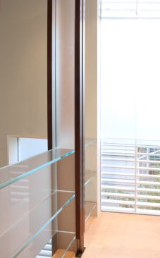 Slender glass shelves echo the form of the window louvers.